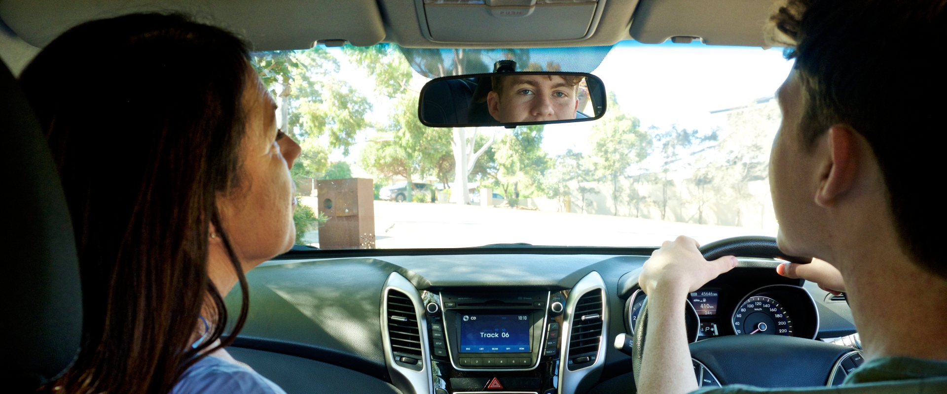 Teenage boy learning to drive with a supervisor in the car with them