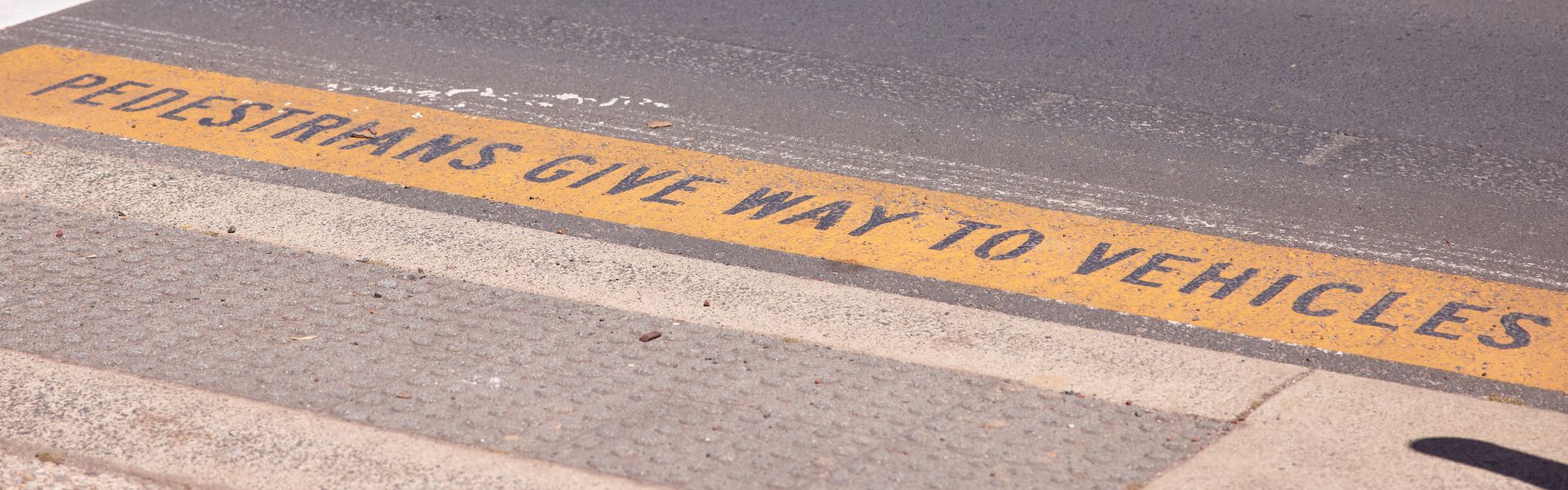 Photo of road with text painted on saying pedestrians give way to vehicles