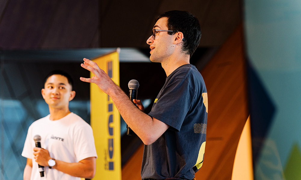 Two men are up on stage talking into microphones