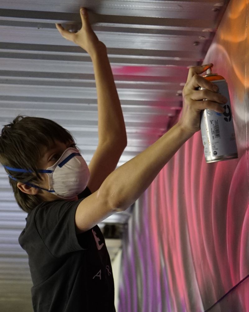 Local youth have a go at street art as they help create the Hub's vibrant mural