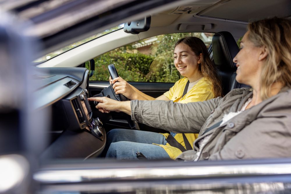 A teenager and their driving supervisor talk through all the functions of the car as they prepare to start driving