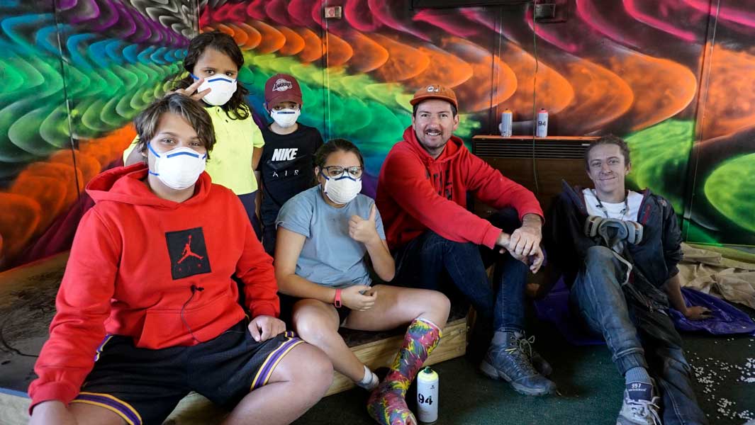 Young locals pose in front of their colourful wall mural