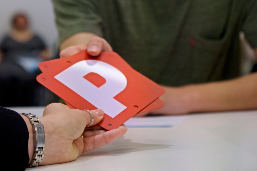 Person handing P plates to another person