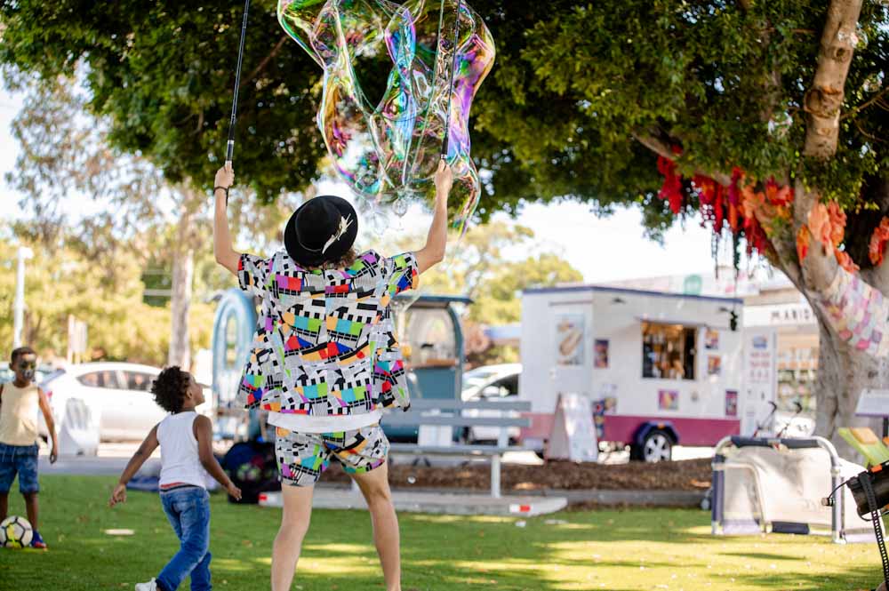 A colourful street performer blows giant bubbles for the children at Gnalla Plaza