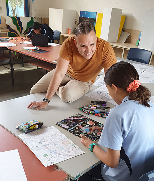 Artist Rhys Paddick is smiling while talking to a student