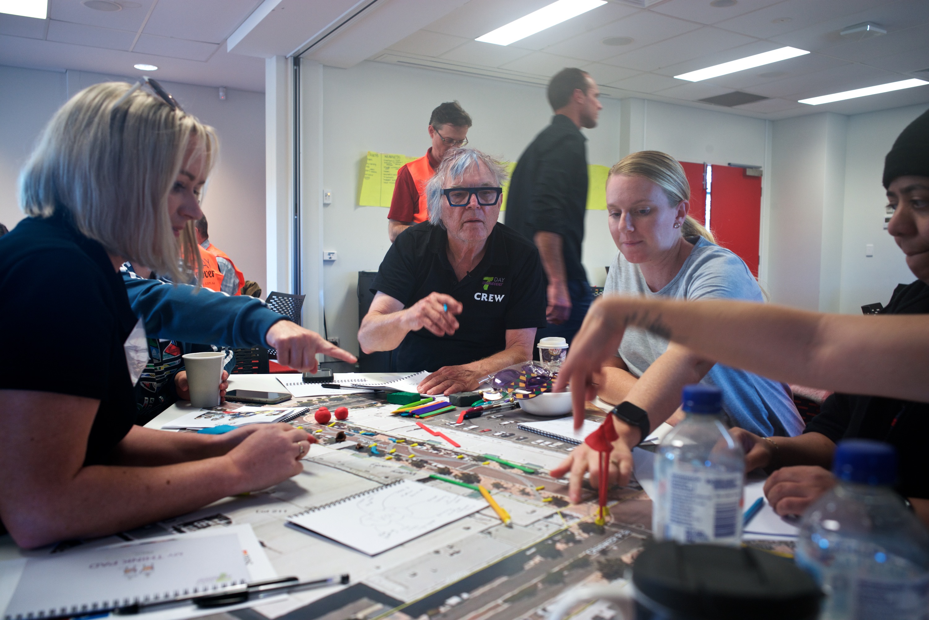A group of people gathered around a table, sketching and discussing plans for their town