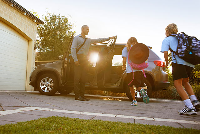 Father opening door of family car for his children