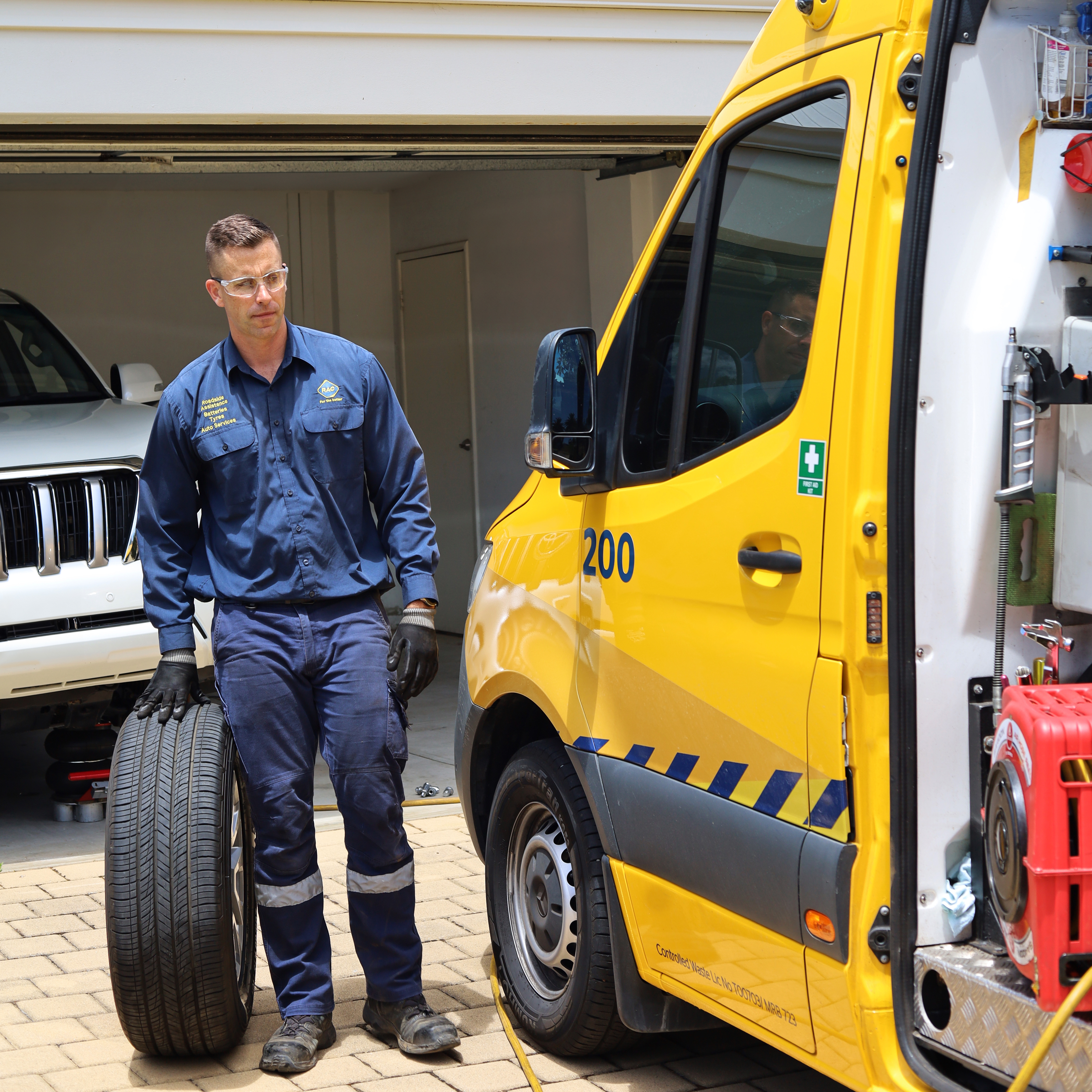 An RAC tyre technician rolling a tyre back into the mobile tyre van
