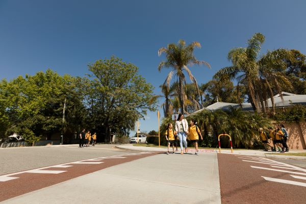 A mother and her two daughters holding hands while crossing the road safely