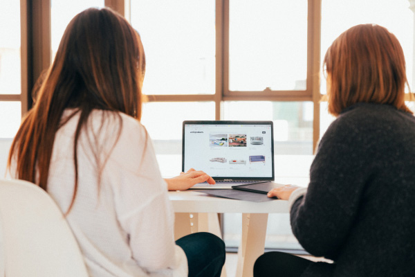 Two people on a table looking at a laptop