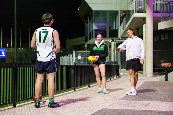 Two male and one female football supporters standing near the stadium talking.