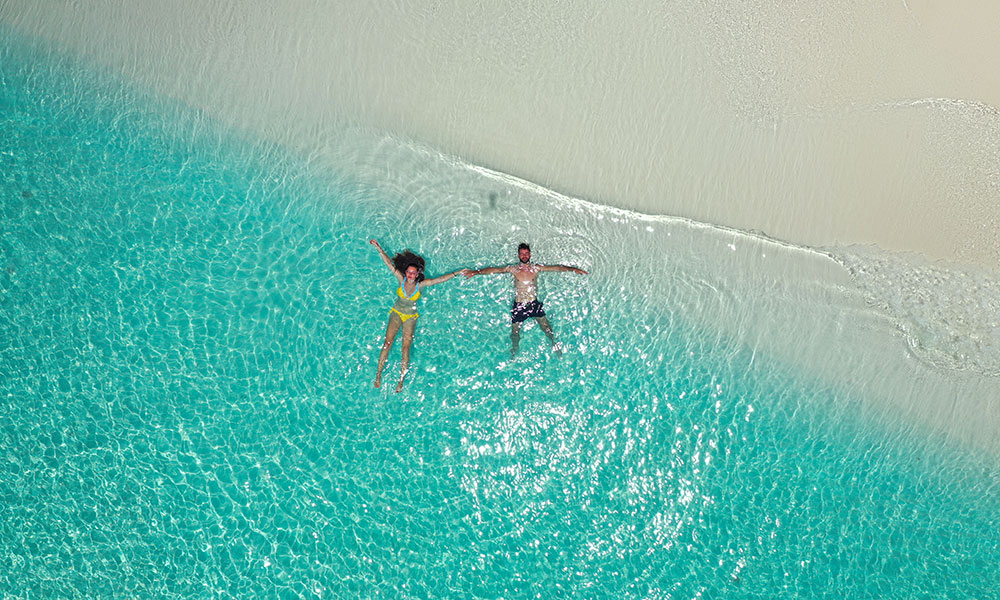A couple are floating together at the beach