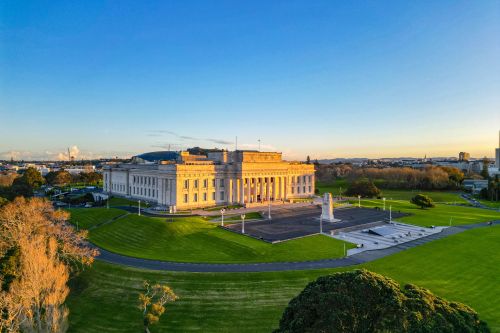 Auckland War Memorial Museum overlooking green parkland at sunset.