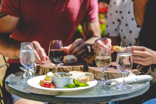 A tasting board with bread olives and cheeses alongside glasses of wine and water