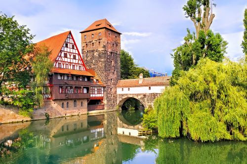 An old European building on a canal with bright green trees