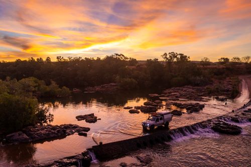 A 4WD at the flooded Ivanhoe Crossing in Kununurra at sunset. 