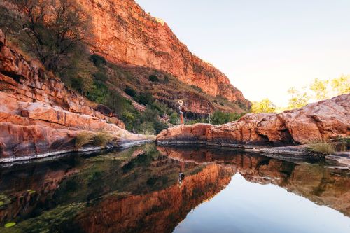 A traveller standing in a gorge between vibrant red rock formations. 