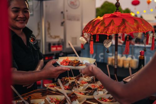 A street food stand with little boats as serving plates. 