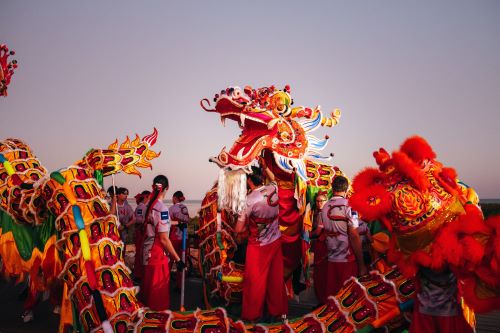Colourful dragon dancers performing at sunset as part of a traditional cultural celebration.