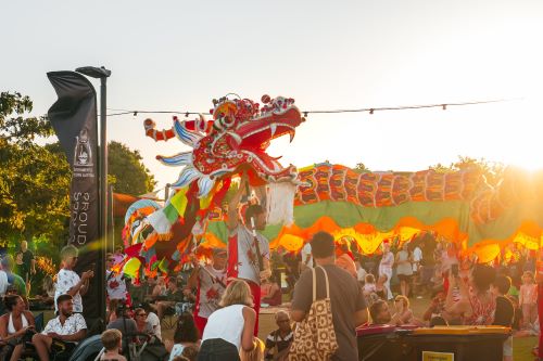 Colourful dragon dancers performing at sunset as part of a traditional cultural celebration.