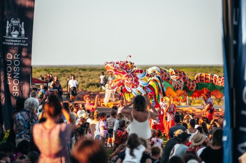 Colourful dragon dancers performing at sunset as part of a traditional cultural celebration.