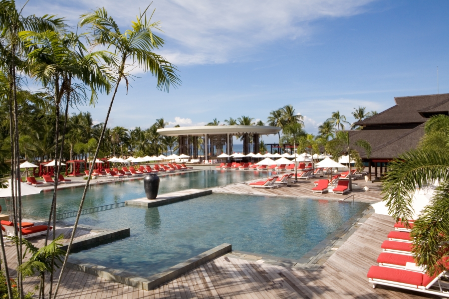 The spacious pool area with lots of lounges and palm trees 