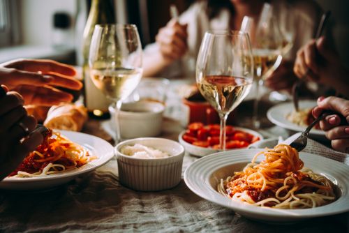 Bowls of spaghetti and glasses of wine on a table