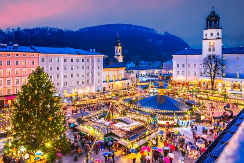 Lit-up Christmas Market in Salzburg with lots of stalls and a big Christmas tree. 