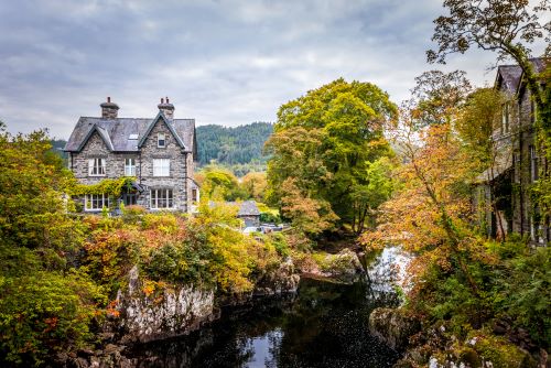 Scenic riverside village in Betws-y-Coed, Snowdonia National Park, surrounded by autumn trees.