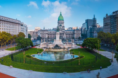 The National Congress building and surrounding plaza in Buenos Aires, featuring a central monument, fountain and landscaped gardens.