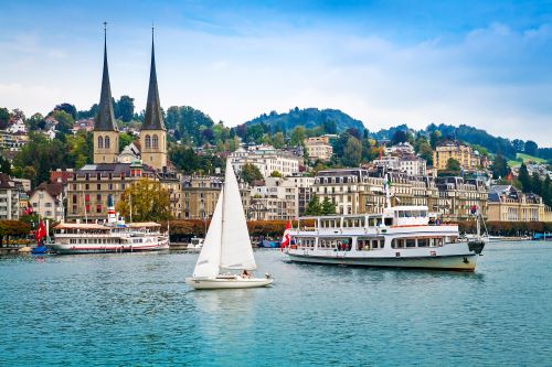 Cityscape of Lucerne with sailing boats and small ships on the lake.