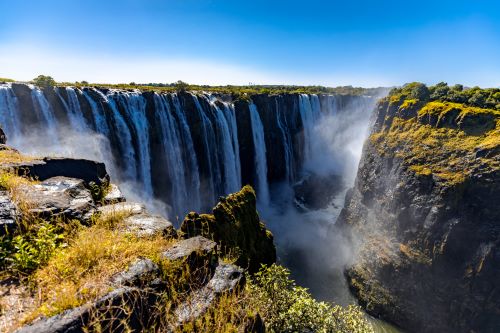 Majestic Victoria Falls on a sunny day against bright blue sky. 