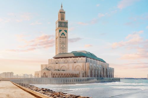 Hassan II Mosque in Casablanca, Morocco, extending over the Atlantic Ocean at sunset.