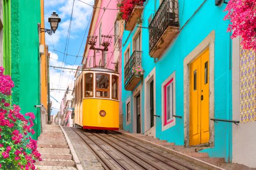 Traditional yellow tram travelling through colourful streets in Lisbon, Portugal