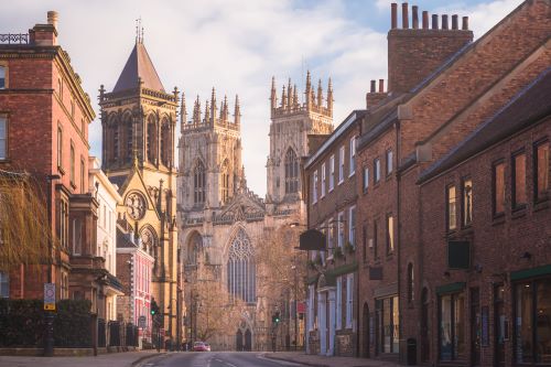  Quiet street leading to the grand gothic-style York Minster Cathedral on a clear morning.