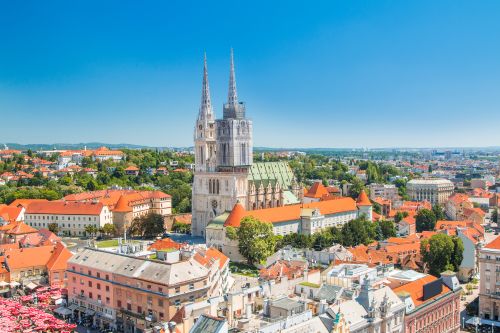 Aerial view of Zagreb, Croatia, featuring Zagreb Cathedral's twin spires rising above the city's historic red-roofed buildings.
