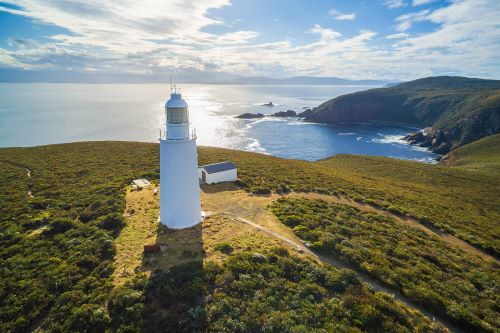 A white lighthouse on a green mountain