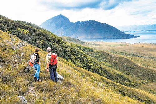 Two hikers standing on a mountain looking out to the scenery