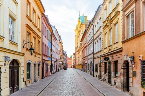 A cobblestone street lined with historic colourful buildings in the middle of Warsaw old town