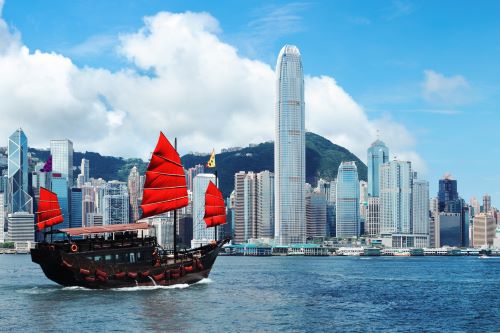 A small boat sailing in front of the Hong Kong skyline