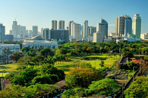 Panoramic view of Manila’s urban skyline with lush greenery and historic structures in the foreground