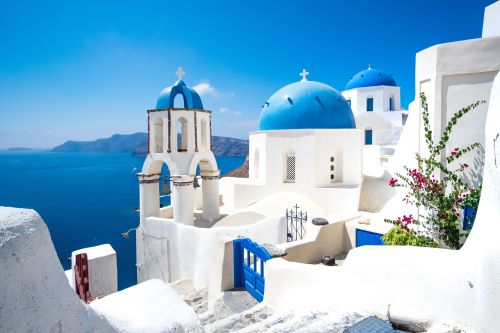 White buildings with blue dome roofs and the bright blue ocean in Santorini