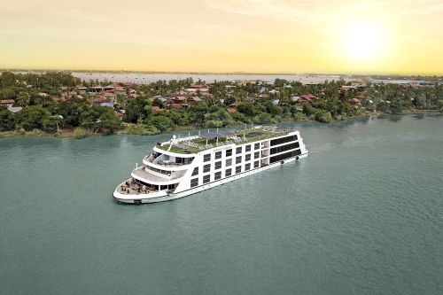 A river ship making it's way through the blue waters with the sun setting behind it