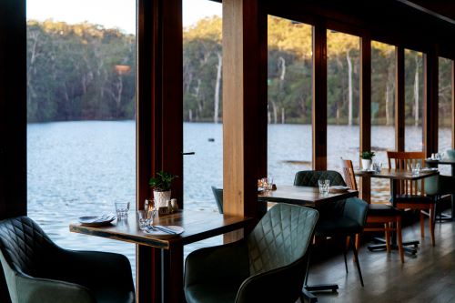 Karri Valley Restaurant with tables and chairs in front of big top to bottom windows overlooking the lake