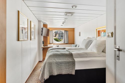 Modern cruise ship cabin with a large bed and round window
