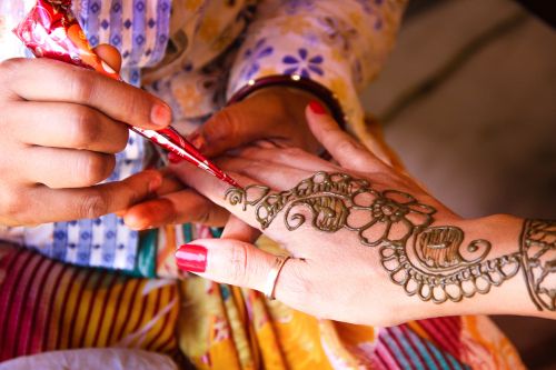 Painting hand with henna in flower design.
