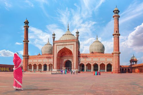 A woman in a red sari stands in the courtyard of Jama Masjid, a grand mosque in Delhi.
