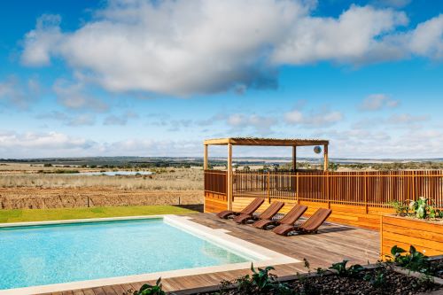 A pool with sun lounges and a vast open landscape in the background. 