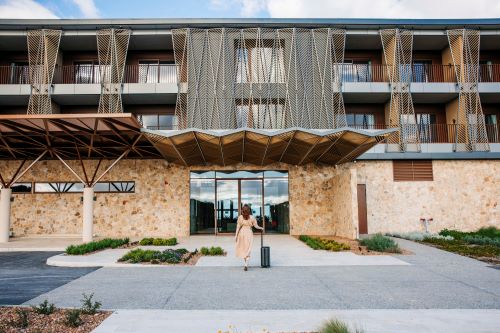 Guest arriving at the entrance of a contemporary stone-fronted hotel with unique architectural details.