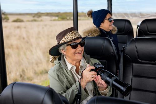 Traveller with a hat and a camera sitting in a safari jeep enjoying the tour. 